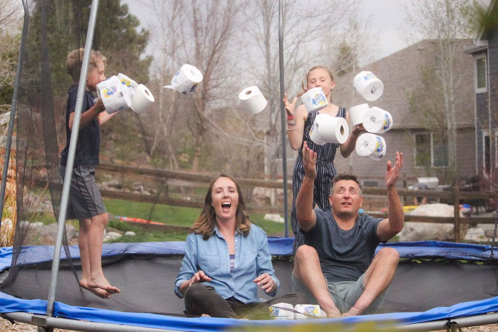 Photo of parents and their young children having a fun time bouncing on a trampoline with rolls of toilet paper in the air. Wall represented this family in the purchase of their home. 